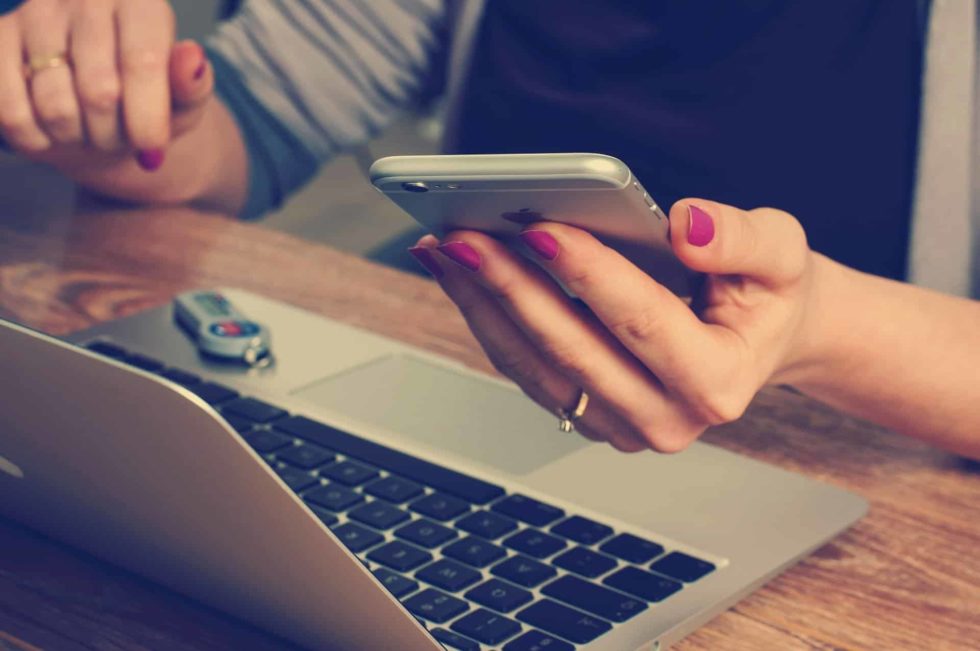 femme sur son smartphone devant un ordinateur