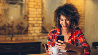 Femme souriant qui tient un téléphone dans la main