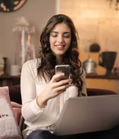 Femme tenant son mobile en main avec son ordinateur sur les genoux