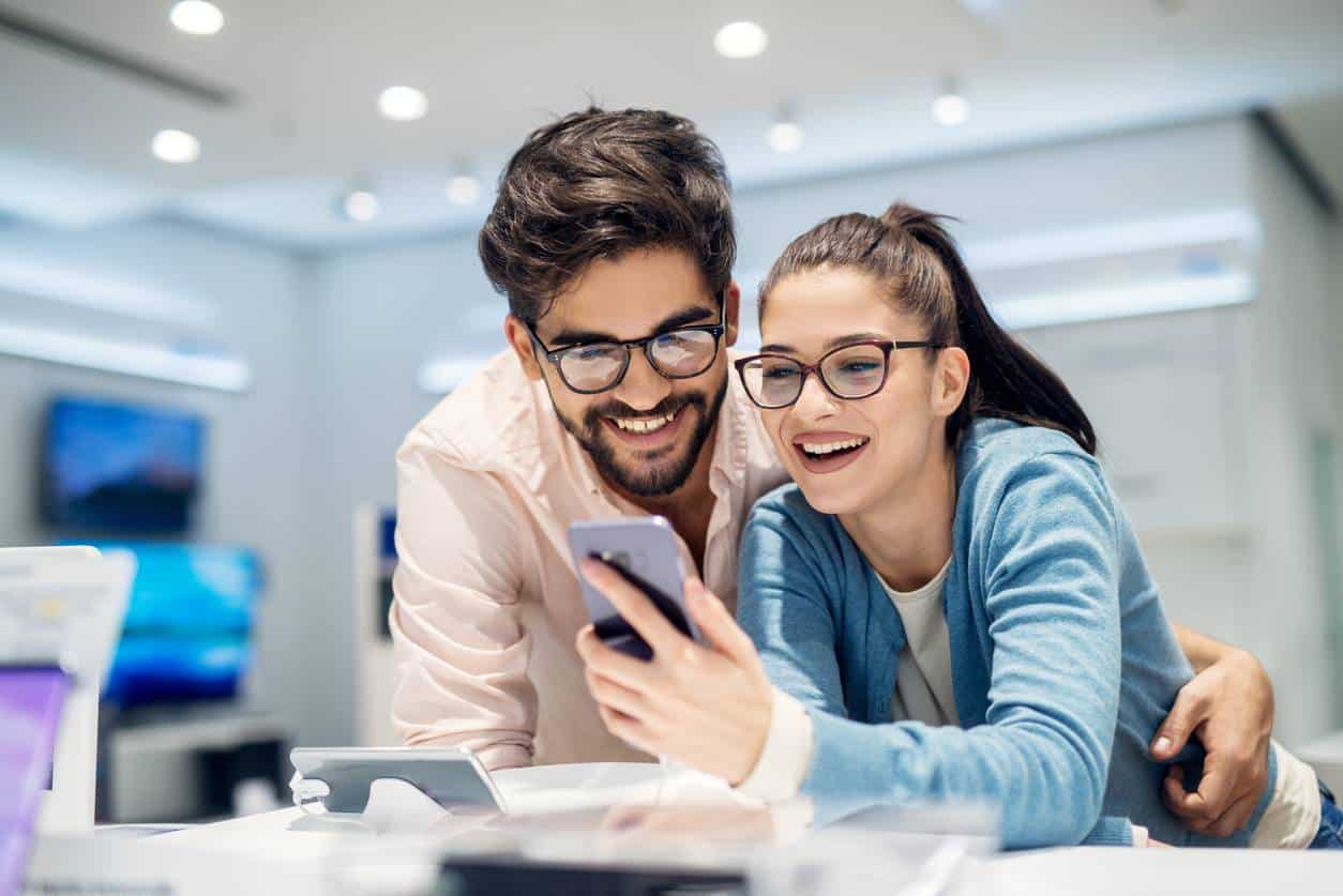 Un homme et une femme souriants devant un téléphone