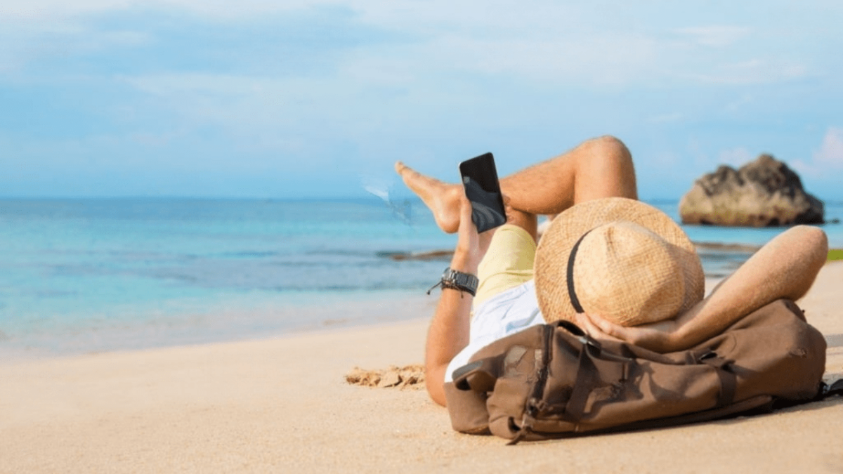 Une personne allongée sur la plage avec son téléphone en main