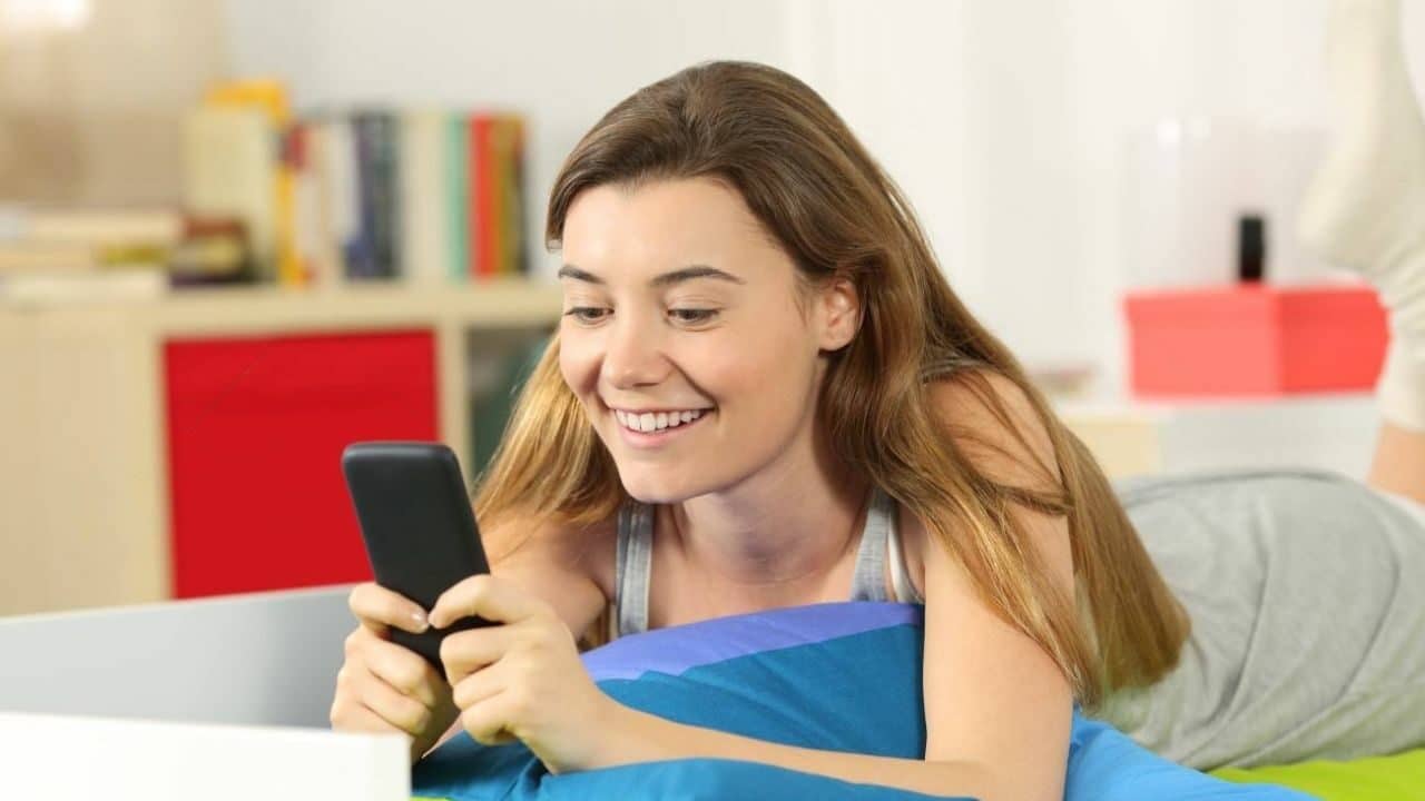 Une jeune fille allongée sur le canapé avec son smartphone en main