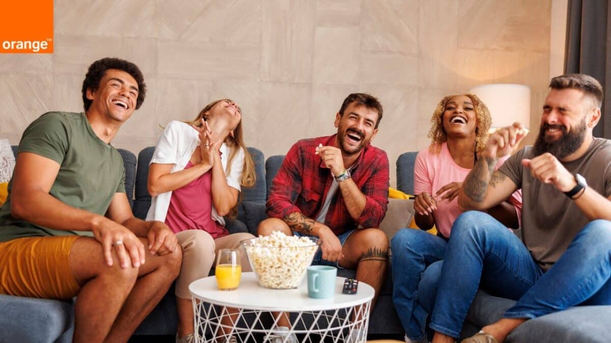 Groupe d'amis mangeant du pop-corn et riant en regardant un film amusant à la télévision à la maison