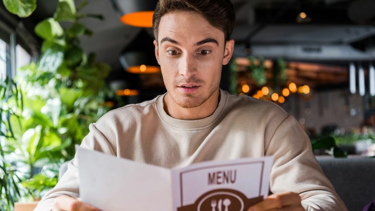 Un homme supris face aux prix d'un menu