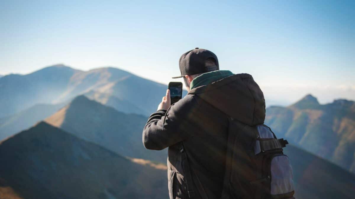 Un homme prenant une photo d'un paysage de montage avec son smartphone