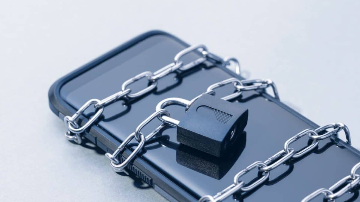 Un smartphone entouré d'une chaine fermée avec un cadenas